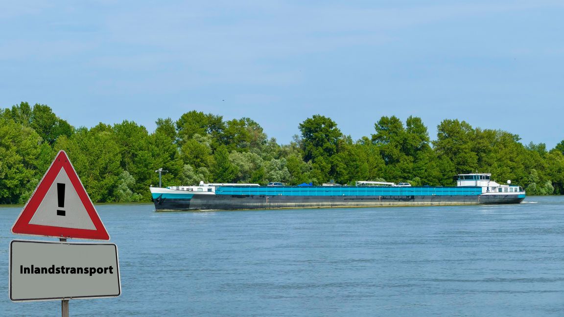 Binnenschiff auf Fluss und Verkehrsschild mit Text "Inlandstransport"